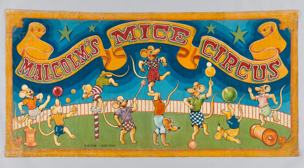 A painted banner with blue background and yellow border depicting numerous cartoon style mice dressed in shirts and tops, performing acrobatic acts in a circus ring.
